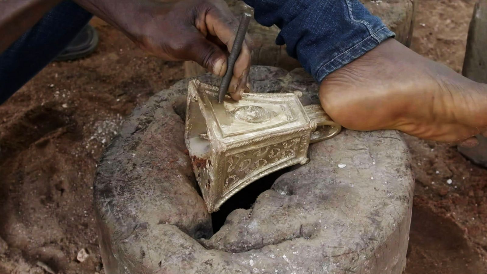 After cooling, the clay shell is broken open, and the surface of the bronze casting is cleaned. Phil Omodamwen then chisels the decorations and polishes the bell.
